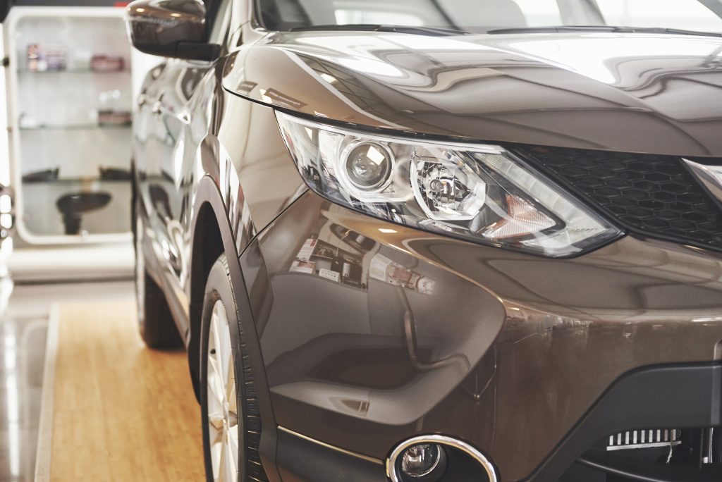 An earthy colored paint on a vehicle with a reflective body, inside a showroom or clean workshop