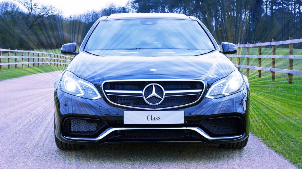 Mercedes, black car, headlights on during daytime, facing camera